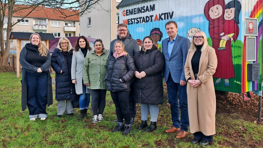 Eine Gruppe Menschen steht draußen vor dem Bauwagen mit der Aufschrift: Gemeinsam Weststadt Aktiv