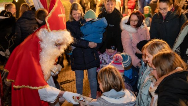 Das Foto zeigt, wie eine als Nikolaus verkleidete Person Geschenke verteilt.