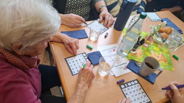 Ein Tisch mit mehreren Bingo-Karten und Händen von Spielenden.